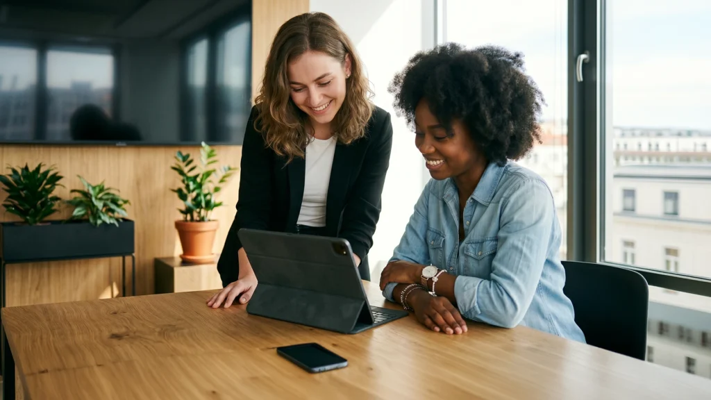 Two women looking at a pharma crm screen on a tablet device.